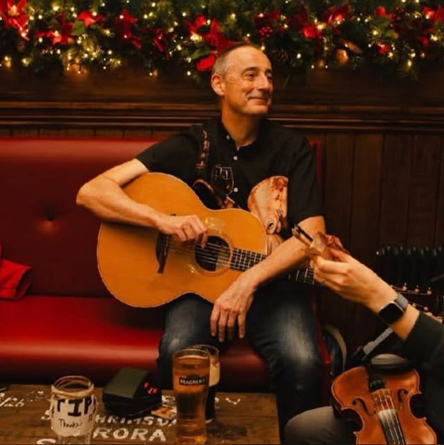 Paul Campbell seated with his acoustic guitar during a traditional music session